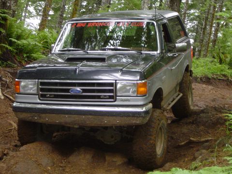 1989 Ford Bronco - This Ford Bronco is navigating a challenging off-road course with steep inclines and loose dirt.