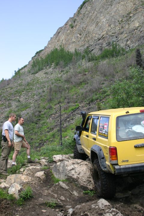 2003 Jeep TJ - Yellow Jeep Cherokee XJ navigates a difficult rocky terrain with two observers.