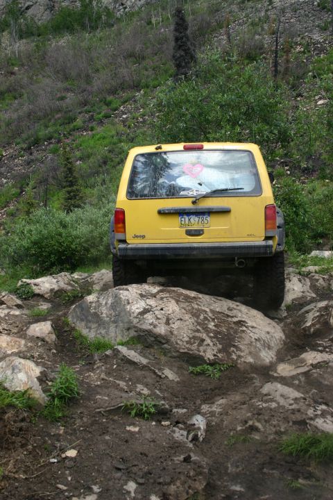 2003 Jeep TJ - Yellow Jeep Cherokee navigates a challenging rocky trail.