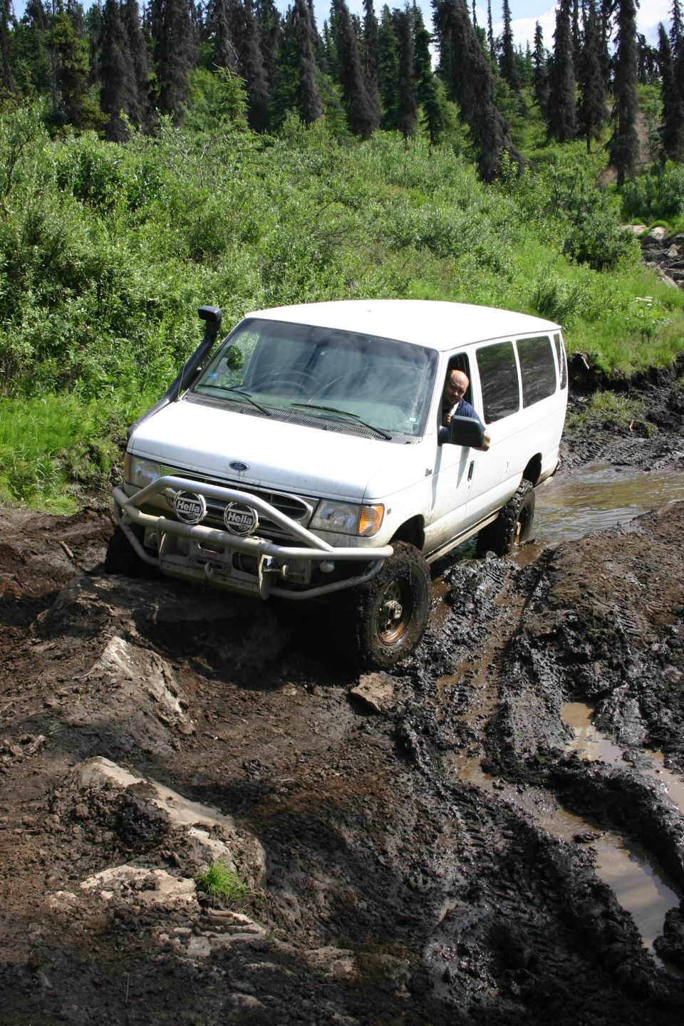 White van with snorkel and brush guard driving through mud and water