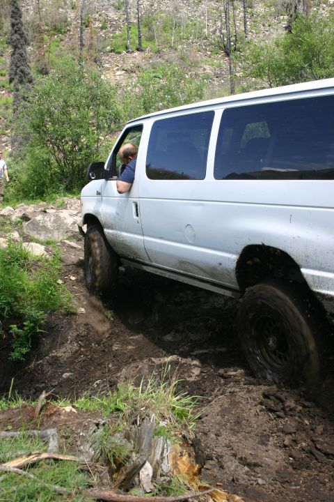 2003 Jeep TJ - A white van navigates a challenging muddy terrain on an off-road trail.