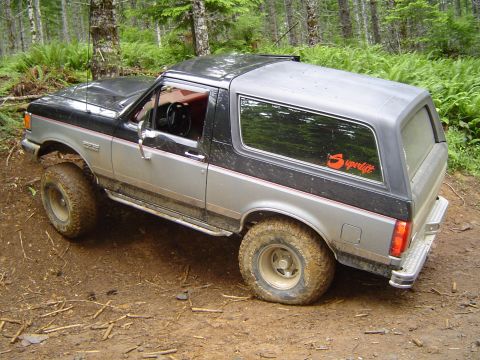 1989 Ford Bronco - This lifted Ford Bronco is navigating a muddy, wooded trail.