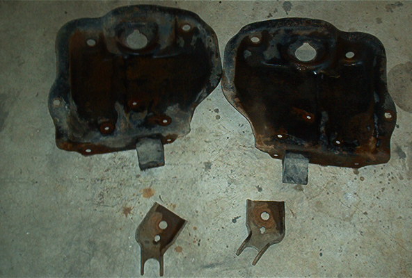 Two rusty metal plates and two brackets on a concrete floor