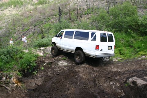 2003 Jeep TJ - A white van navigates a challenging off-road course on a steep, wooded hillside.