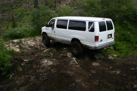 2003 Jeep TJ - A white van, modified for off-road use, carefully maneuvers over a challenging rocky path.