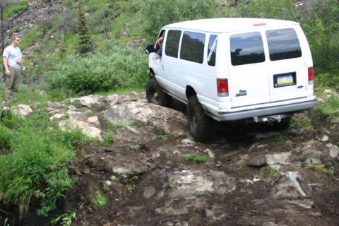 2003 Jeep TJ - A white van navigates a challenging rocky and muddy off-road course.