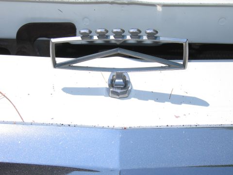 1991 Ford LTD Crown Victoria - Close-up of a chrome hood ornament with a distinctive triangular design and five studs.