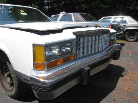 1991 Ford LTD Crown Victoria - Front view of a white Ford Crown Victoria with its hood open, parked outdoors with other vehicles.