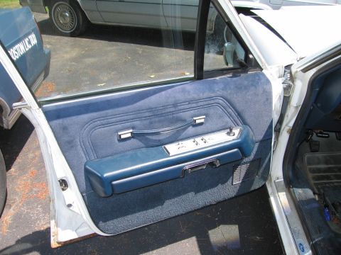 1991 Ford LTD Crown Victoria - Interior view of a blue door panel with chrome accents and power controls, with another vehicle visible outside.