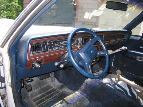 1991 Ford LTD Crown Victoria - Interior view of a car's dashboard, steering wheel, and front seats, showing the driver's side controls and carpeting.