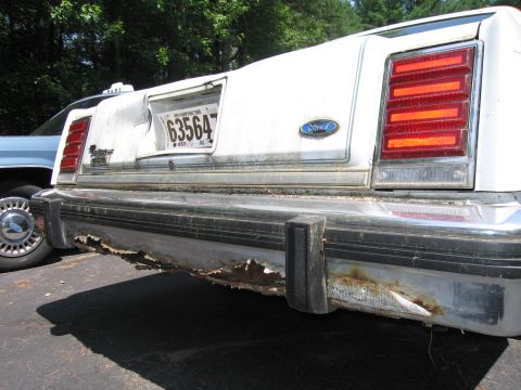 1991 Ford LTD Crown Victoria - Rear view of a white 1991 Ford Crown Victoria taxi with a severely rusted bumper and a New Hampshire license plate.