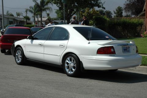 1993 Ford Taurus - This white sedan features a rear spoiler and chrome wheels, with a license plate visible.