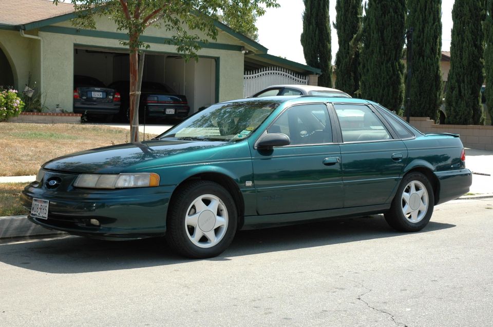 Green sedan parked on street, front quarter view. License plate visible