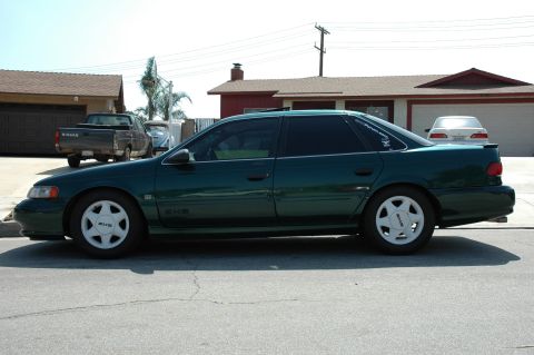 1993 Ford Taurus - Side view of a green sedan parked on a residential street.