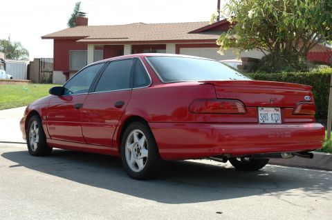 1993 Ford Taurus - Rear view of a red 1993 Ford Taurus SHO sedan parked on a residential street.