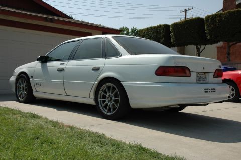 1993 Ford Taurus - Rear view of a white sedan with aftermarket wheels and a California license plate.