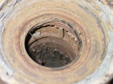 1995 Ford Bronco - Looking straight down into the rusted bore of a heavy cylindrical steel component, with flaking corrosion and dirt coating the machined ste…