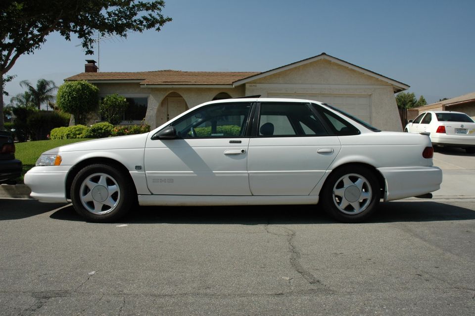 white 1993 Ford Taurus parked on street, house in background