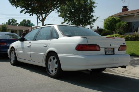 1993 Ford Taurus - A white 1992 Ford Taurus sedan is parked on a residential street, showing its rear and side profile.