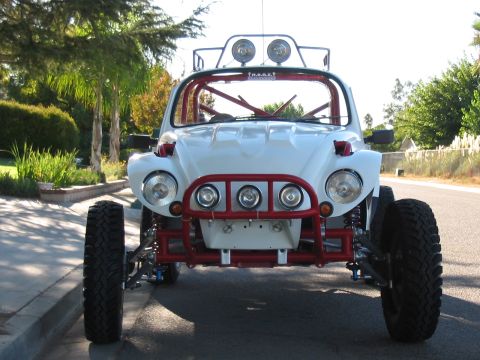 1990 Ford Bronco - Front-on view of a white VW Beetle off-road buggy with a red front bar, light pods and roof-mounted lights on a street.