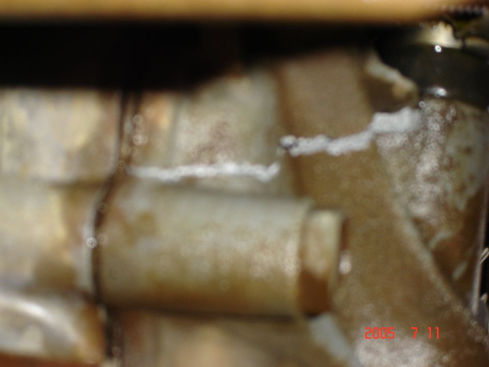 Close-up of a corroded metal water pump component with white residue
