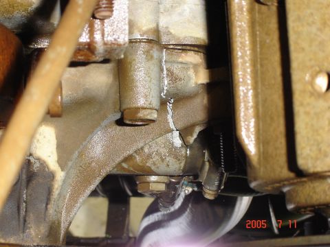 1993 Ford Bronco - Close-up view of a cracked engine block, showing signs of fluid leakage and mechanical components.