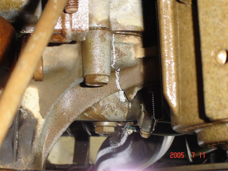 Cracked engine block with visible fluid leaks and bolts