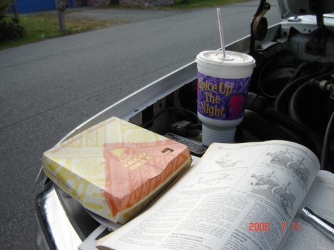 1993 Ford Bronco - A Taco Bell meal and drink sit on the engine of a vehicle next to an open service manual.
