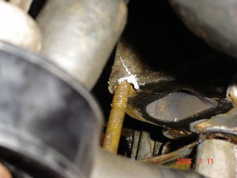 1993 Ford Bronco - Close-up of a corroded engine part with a rusty bolt and visible sealant.