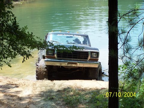 1987 Ford Bronco - A lifted 1978 Ford Bronco, identified by its body style, is shown entering a body of water. The windshield displays 'JEEP RESCUE TEAM'.