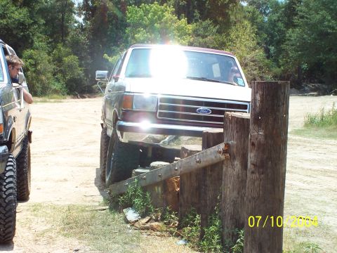 1987 Ford Bronco - A white Ford Bronco navigates an obstacle course, with another vehicle visible to the left.