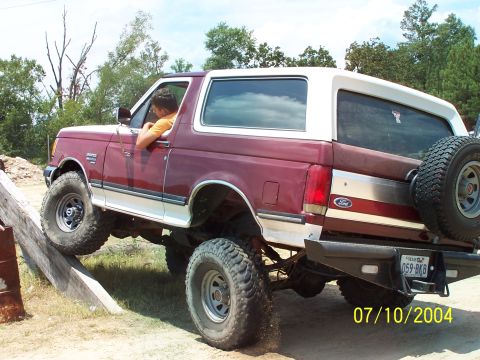 1987 Ford Bronco - 1987 Ford Bronco navigating an off-road course with a driver inside.