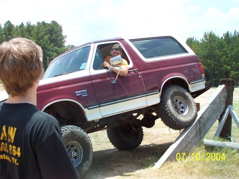 1987 Ford Bronco - A maroon and white 1987 Ford Bronco navigates an off-road obstacle course.