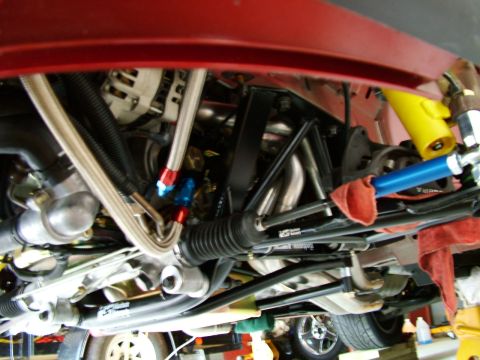 2003 Ford Mustang - Undercarriage view reveals braided hoses and exhaust headers within the engine bay.