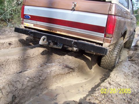1987 Ford Bronco - This 1987 Ford Bronco is stuck in a muddy track, showing its rear end and off-road tires.