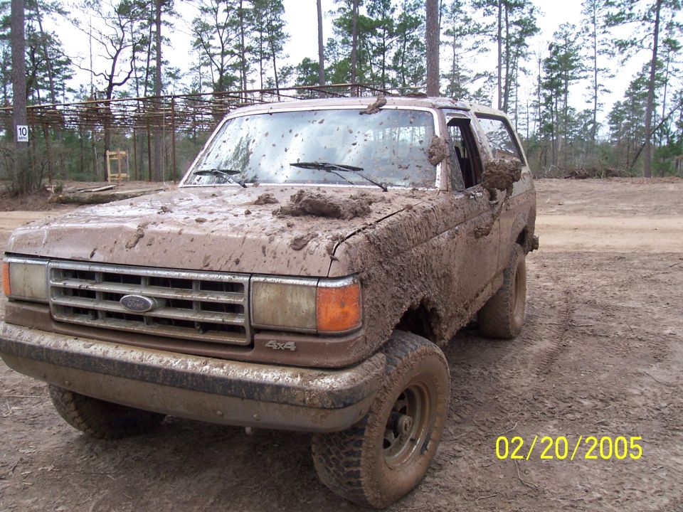 Mud-covered 1987 Ford Bronco, 3/4 front view, with visible grille and 4x4 badge