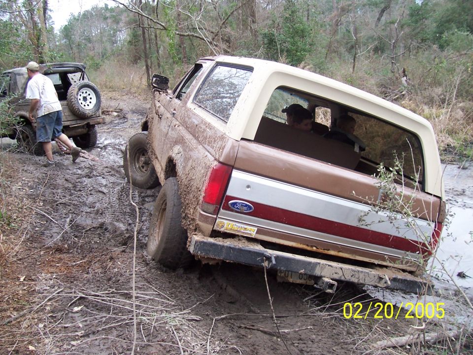 1987 Ford Bronco stuck in mud, another off-road vehicle behind it