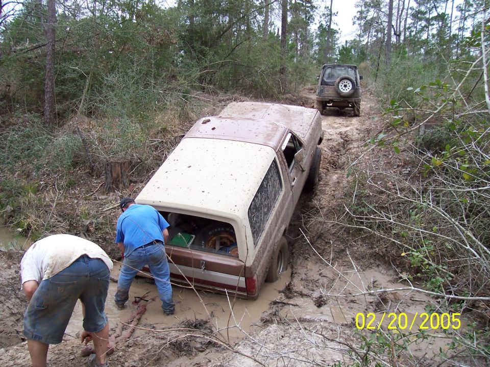 Brown 1987 Ford Bronco stuck in mud with two men nearby