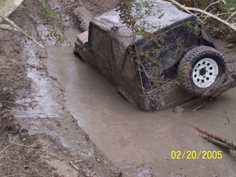 1987 Ford Bronco - This 1987 Ford Bronco is deeply stuck in a muddy ditch, with vegetation growing around it.