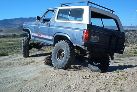 1986 Ford Bronco - This modified Ford Bronco is tackling a steep, dusty incline under a clear blue sky.