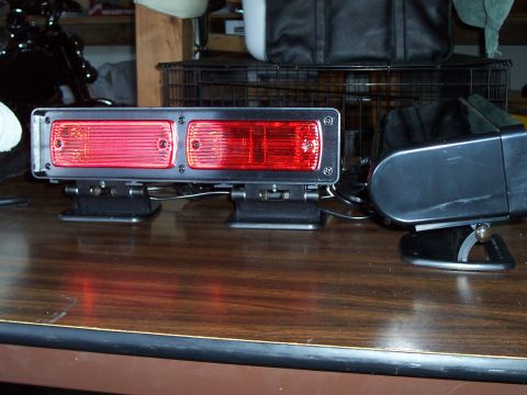 2003 Ford Crown Victoria - Dual red strobes are mounted on a wooden desk, with a black object to the right.