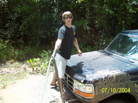 1987 Ford Bronco - A person washes a muddy black SUV in an outdoor setting, with a date stamp of 07/10/2004 visible on the image.