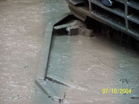 1987 Ford Bronco - 1987 Ford Bronco stuck in mud, showing front bumper and grille.