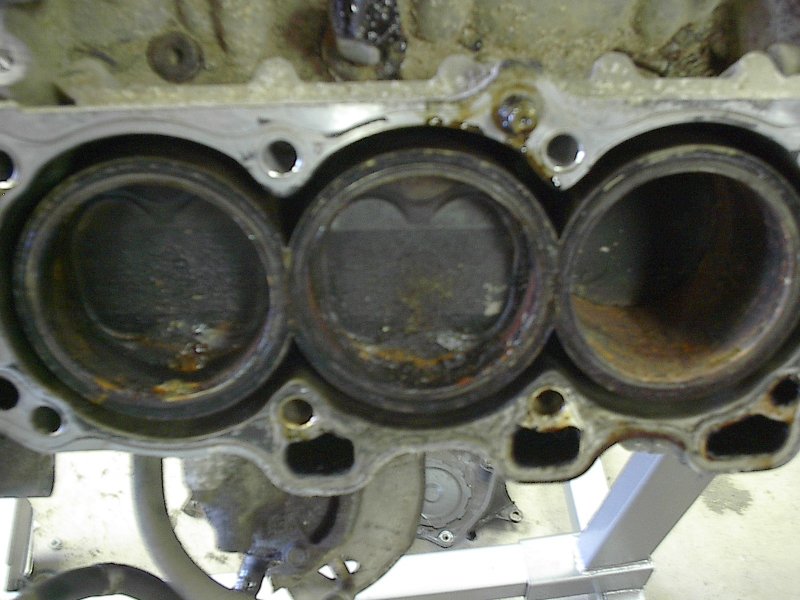 Close-up of three engine cylinders, showing wear and rust