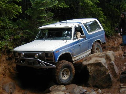 1994 Ford Explorer - This blue and white SUV, likely from the 1980s, is shown tackling a challenging rocky trail.