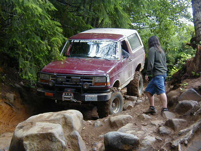 Maroon Ford Bronco with ARB winch bumper descending a rocky forest trail
