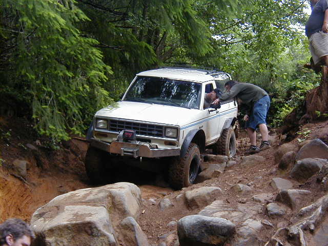 White off-road SUV with winch on rocky trail. Appears to be a Ford Bronco II