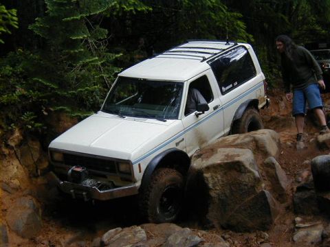 1994 Ford Explorer - A white SUV navigates a rocky trail with a person watching.