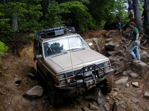 1994 Ford Explorer - A Jeep Cherokee XJ navigates a challenging rocky off-road trail with people watching.