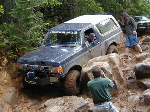 1994 Ford Explorer - A group of people are off-roading with their Ford Broncos on a challenging, rocky terrain.